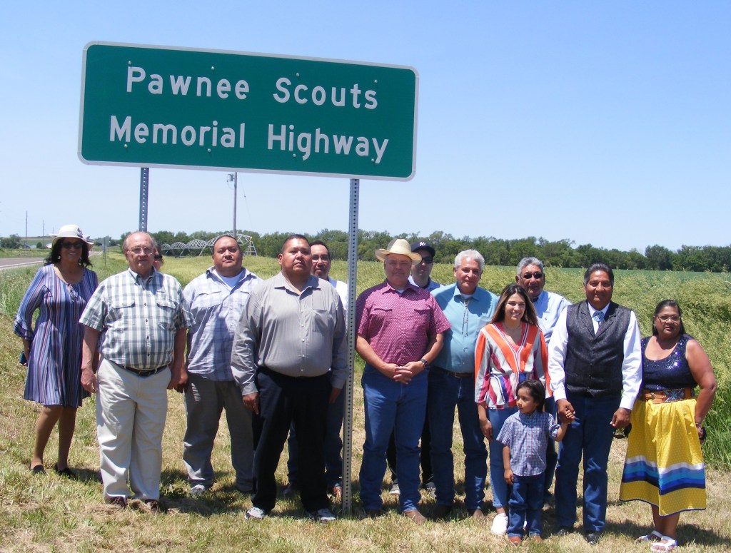 Group photo of people gathered beneath Pawnee Scouts Memorial Highway sign.